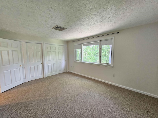 302 Eastview Dr, Wilton, NH 03086 - unfurnished bedroom with multiple closets, a textured ceiling, carpet floors, and baseboards