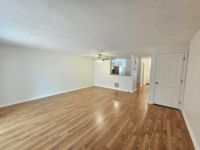 302 Eastview Dr, Wilton, NH 03086 - unfurnished living room with a ceiling fan, light wood finished floors, a textured ceiling, and baseboards