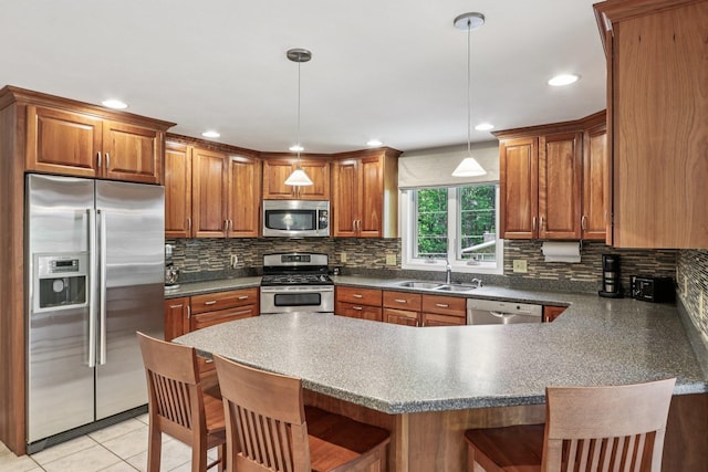 2 Warton Rd, Nashua, NH 03062 - kitchen with stainless steel appliances, a sink, a peninsula, a kitchen bar, and brown cabinets