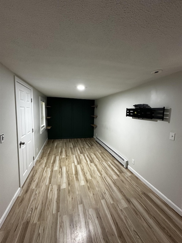 30 Flat Rock Bridge Rd, Rochester, NH 03868 - unfurnished living room with a baseboard heating unit, wood finished floors, baseboards, and a textured ceiling