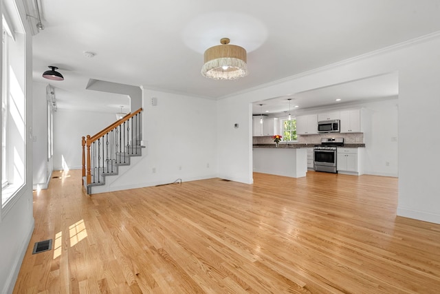 250 Harmony Rd, Northwood, NH 03261 - unfurnished living room featuring light wood-type flooring, stairs, baseboards, and ornamental molding