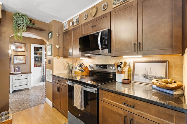 228 Platts Ave, Manchester, NH 03109 - kitchen featuring stainless steel appliances, light wood-style floors, dark stone counters, decorative backsplash, and arched walkways