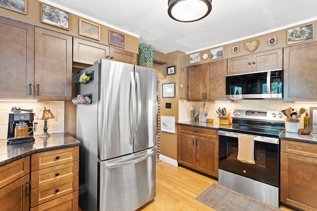 228 Platts Ave, Manchester, NH 03109 - kitchen featuring appliances with stainless steel finishes, tasteful backsplash, light wood-style floors, and dark stone counters