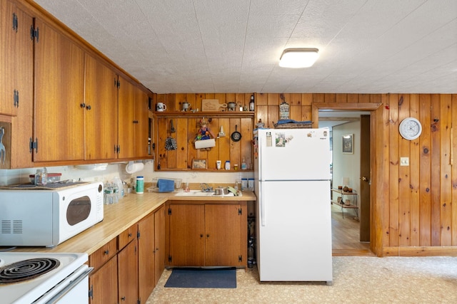 87 Lower Camp Rd, Northwood, NH 03261 - kitchen featuring white appliances, light countertops, a sink, wood walls, and brown cabinets