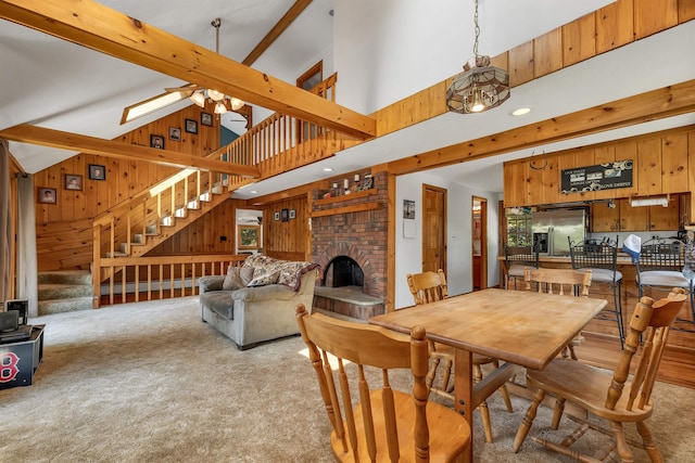 222 Main St, Alton, NH 03809 - carpeted dining room with wood walls, stairway, beamed ceiling, a fireplace, and high vaulted ceiling