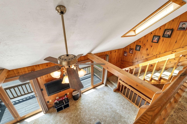222 Main St, Alton, NH 03809 - unfurnished living room featuring wood walls, carpet flooring, a textured ceiling, vaulted ceiling, and a skylight