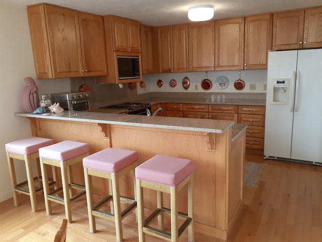11 Portside Dr Unit 5, Moultonborough, NH 03254 - kitchen featuring white refrigerator with ice dispenser, black microwave, light wood-style flooring, stainless steel gas stove, and light countertops