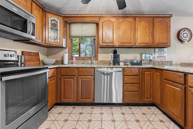 396 Huse Rd, Manchester, NH 03103 - kitchen with stainless steel appliances, brown cabinetry, and light stone countertops