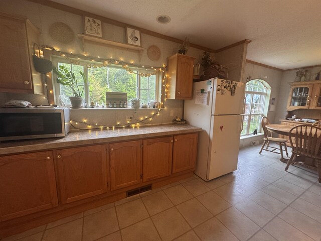 182 Franks Way, Middlesex, VT 05602 - kitchen with freestanding refrigerator, stainless steel microwave, ornamental molding, a textured ceiling, and light tile patterned floors