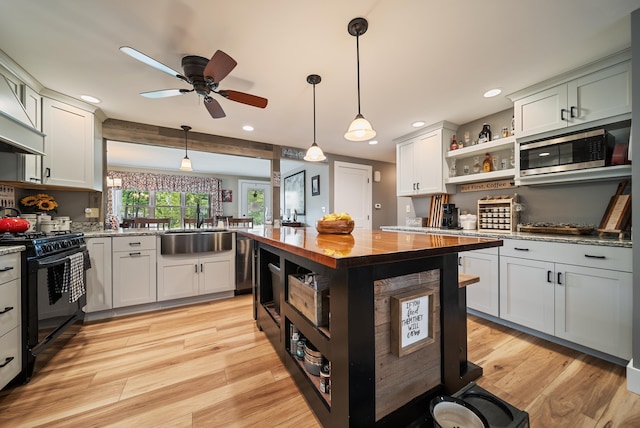 22 Westray Dr, Nashua, NH 03062 - kitchen with open shelves, black gas stove, a sink, stainless steel microwave, and wooden counters