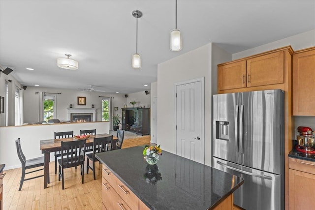 168 Raven Cir, Williston, VT 05495 - kitchen featuring stainless steel fridge, a warm lit fireplace, open floor plan, light wood finished floors, and a ceiling fan