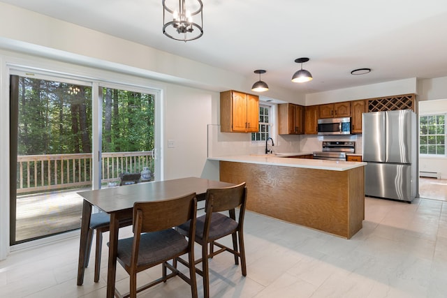 179 Arbor Ln, Colchester, VT 05446 - kitchen featuring stainless steel appliances, a peninsula, brown cabinetry, light countertops, and baseboard heating