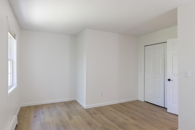 179 Arbor Ln, Colchester, VT 05446 - unfurnished bedroom with a baseboard radiator, light wood-style flooring, a closet, and baseboards