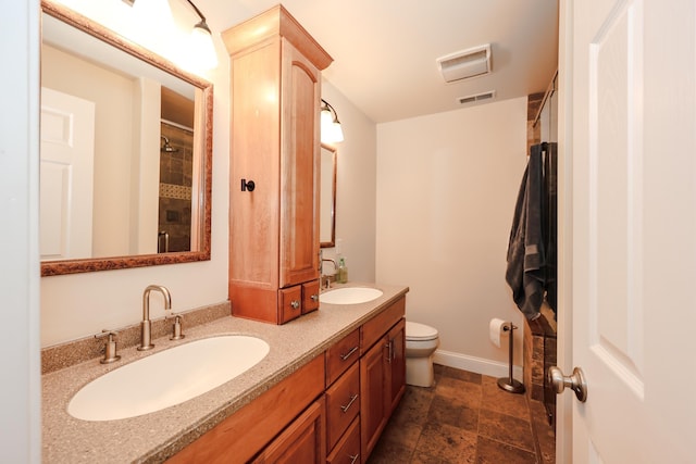 65 Victoria St Unit 8, Manchester, NH 03104 - full bathroom with double vanity, toilet, a shower, stone finish flooring, and baseboards