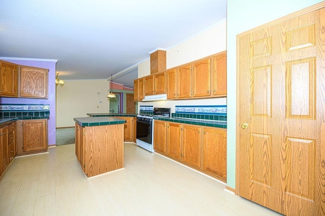 19/22 River St, Seabrook, NH 03874 - kitchen featuring range with gas cooktop, light wood-style floors, a center island, under cabinet range hood, and brown cabinetry