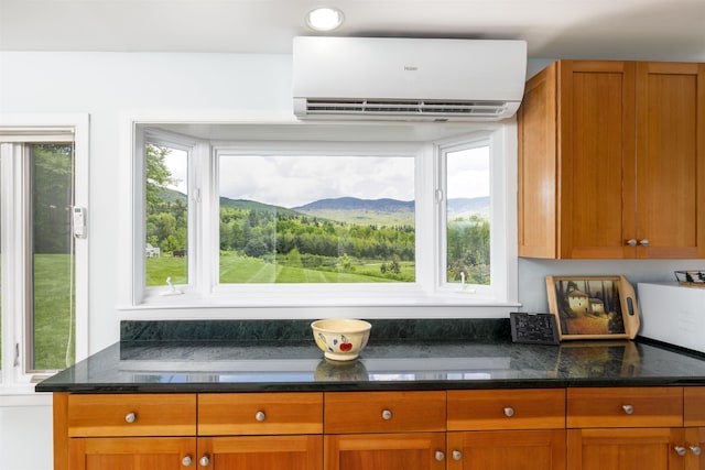 188 Foster Farm Rd, Stowe, VT 05672 - kitchen with a wall mounted air conditioner, healthy amount of natural light, dark stone countertops, and brown cabinetry