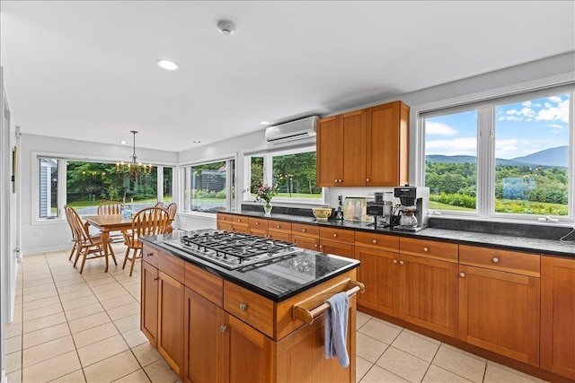 188 Foster Farm Rd, Stowe, VT 05672 - kitchen featuring a wall mounted AC, light tile patterned flooring, brown cabinetry, stainless steel gas stovetop, and a kitchen island