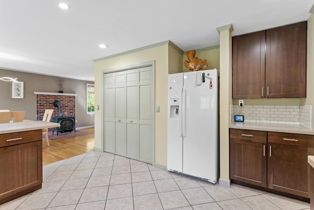 12 Old Fort Ln, Dunbarton, NH 03046 - kitchen featuring white fridge with ice dispenser, light countertops, tasteful backsplash, a wood stove, and ornamental molding