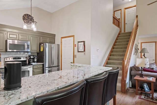 10 Mountain Brook Cir Unit 2, Lincoln, NH 03251 - kitchen with stainless steel appliances, high vaulted ceiling, a breakfast bar, light stone countertops, and light wood-type flooring