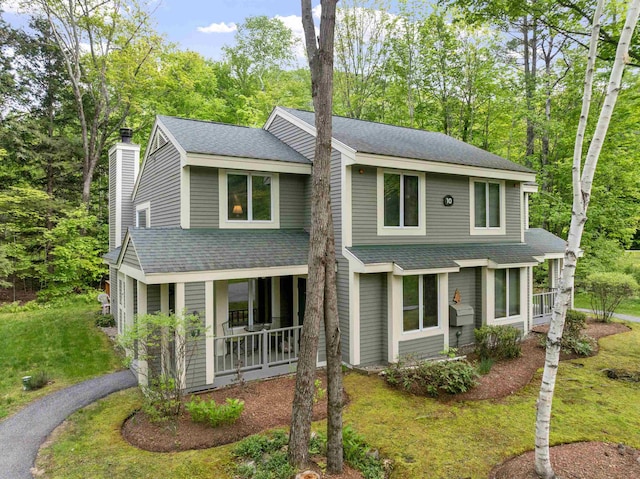 10 Mountain Brook Cir Unit 2, Lincoln, NH 03251 - view of front of property with a shingled roof, covered porch, a front yard, a chimney, and view of scattered trees