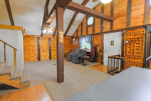 594 Suncook Valley Rd, Alton, NH 03809 - carpeted living area featuring wood walls, ceiling fan, beamed ceiling, high vaulted ceiling, and stairway