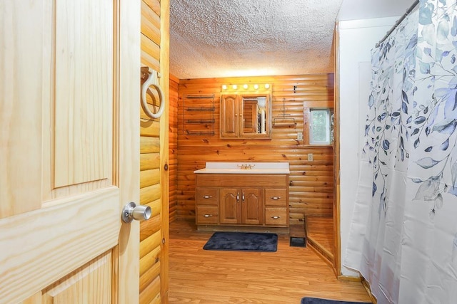 594 Suncook Valley Rd, Alton, NH 03809 - bathroom featuring rustic walls, vanity, wood finished floors, a textured ceiling, and curtained shower
