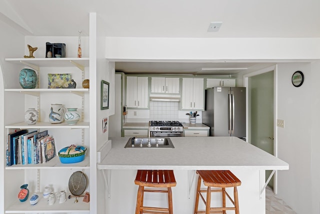 1065 Center Fayston Rd, Fayston, VT 05660 - kitchen with appliances with stainless steel finishes, a peninsula, under cabinet range hood, light countertops, and a breakfast bar area