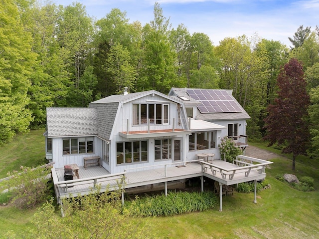 1065 Center Fayston Rd, Fayston, VT 05660 - rear view of property featuring solar panels, roof with shingles, a deck, a gambrel roof, and board and batten siding