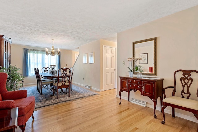 4 Edith Ave, Nashua, NH 03064 - dining room with a chandelier, light wood finished floors, baseboards, and a textured ceiling
