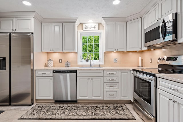 4 Edith Ave, Nashua, NH 03064 - kitchen with appliances with stainless steel finishes, a sink, white cabinetry, backsplash, and a textured ceiling
