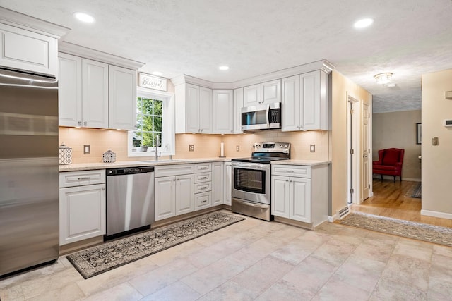 4 Edith Ave, Nashua, NH 03064 - kitchen with stainless steel appliances, a sink, baseboards, light countertops, and backsplash
