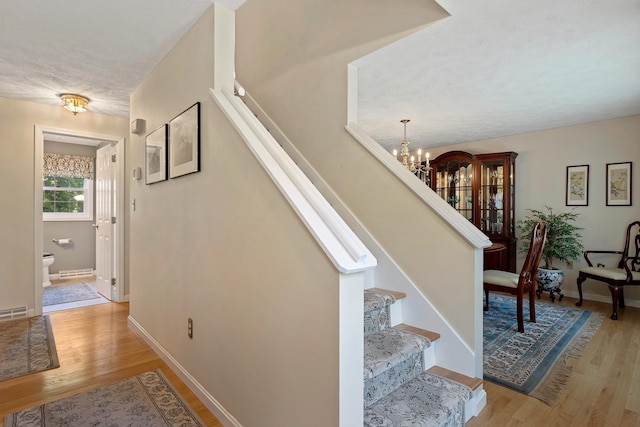 4 Edith Ave, Nashua, NH 03064 - staircase with wood finished floors, a chandelier, and baseboards