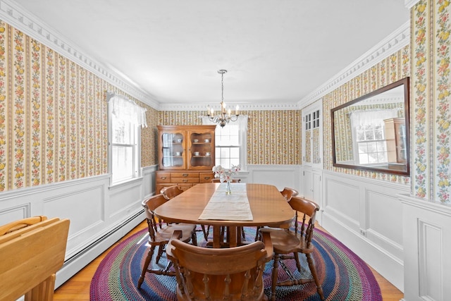 3 Patton St, Rochester, NH 03867 - dining area with a chandelier, baseboard heating, wallpapered walls, wood finished floors, and a wainscoted wall