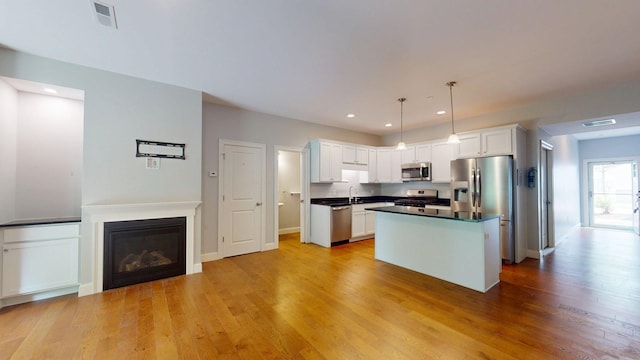 5 Callaway Dr Unit 2, Concord, NH 03301 - kitchen featuring appliances with stainless steel finishes, white cabinetry, light wood-style floors, dark countertops, and a center island