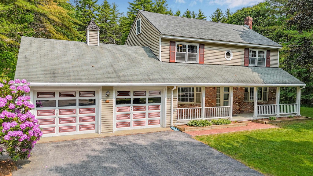 60 Hutchins St, Concord, NH 03303 - view of front facade featuring a chimney, covered porch, an attached garage, asphalt driveway, and a front yard