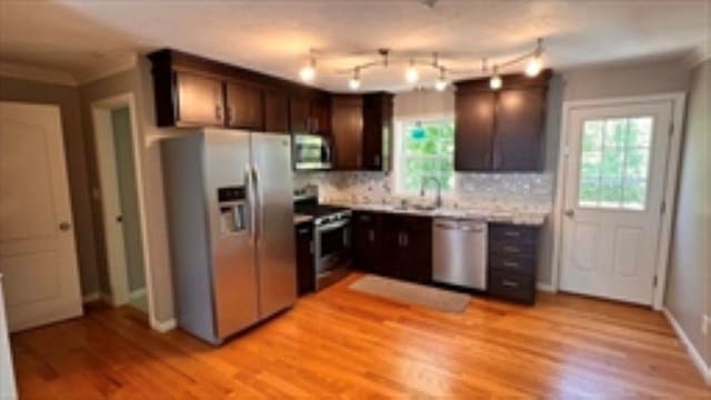 24 Bandon Cir, Westford, MA 01886 - kitchen featuring stainless steel appliances, dark brown cabinets, light wood-type flooring, decorative backsplash, and a sink