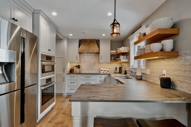 60 Weirs Rd Unit H1, Gilford, NH 03249 - kitchen with stainless steel fridge, open shelves, custom range hood, a peninsula, and light wood-type flooring