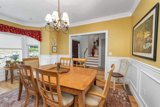 4 Mountain Ridge Dr, Meredith, NH 03253 - dining area featuring a chandelier, ornamental molding, light wood-style floors, wainscoting, and a decorative wall