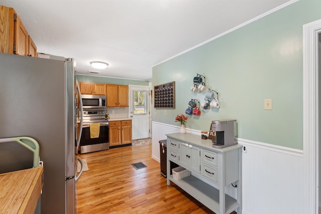 45 Cohas Ave, Manchester, NH 03109 - kitchen featuring stainless steel appliances, light wood-style floors, ornamental molding, a wainscoted wall, and light countertops