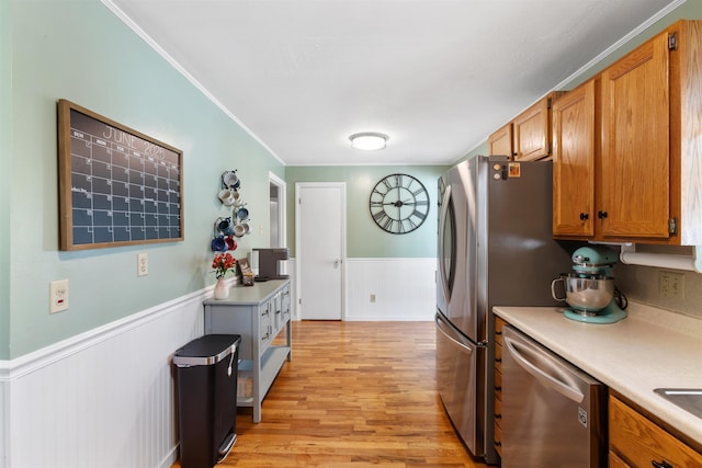 45 Cohas Ave, Manchester, NH 03109 - kitchen featuring stainless steel dishwasher, wainscoting, light countertops, light wood finished floors, and brown cabinets