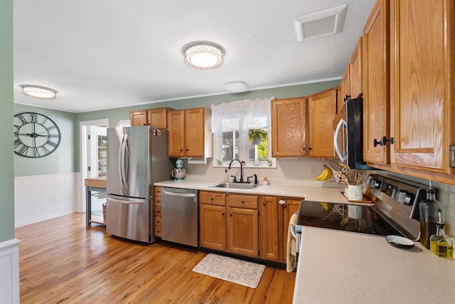45 Cohas Ave, Manchester, NH 03109 - kitchen featuring appliances with stainless steel finishes, a sink, light wood-style flooring, light countertops, and wainscoting