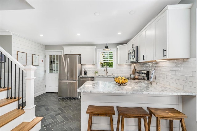 85 Lee Ave, Manchester, NH 03109 - kitchen featuring stainless steel appliances, a sink, decorative backsplash, light stone countertops, and a peninsula
