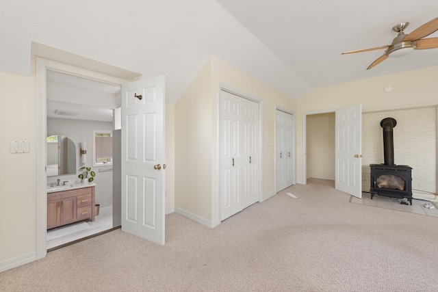 110 Heights Rd, Gilford, NH 03249 - unfurnished living room with a wood stove, light carpet, ceiling fan, a sink, and lofted ceiling