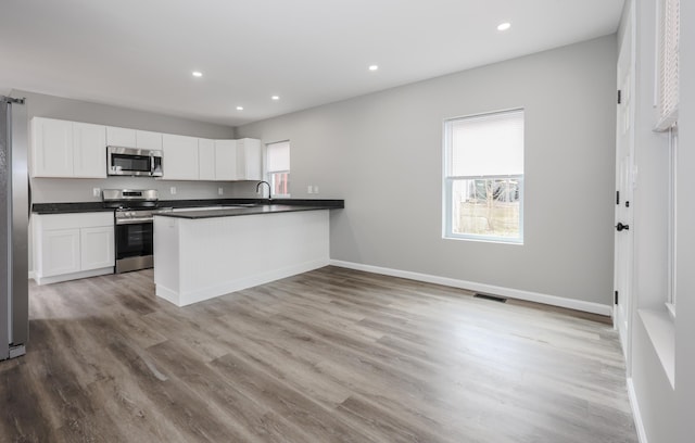 319 Mechanic St, Laconia, NH 03246 - kitchen with stainless steel appliances, a sink, white cabinetry, a peninsula, and recessed lighting