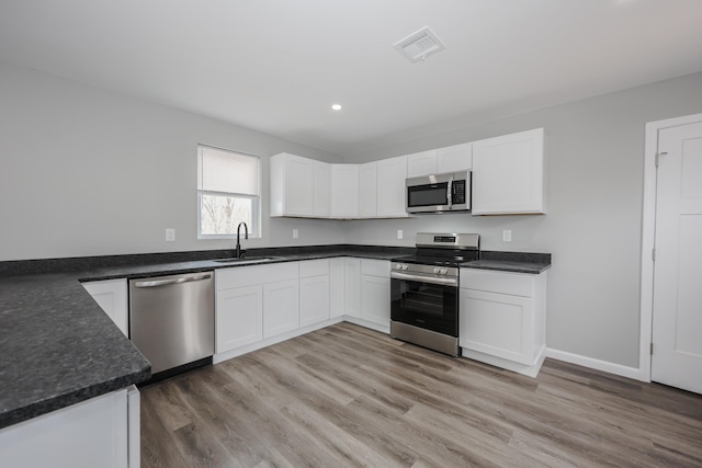 319 Mechanic St, Laconia, NH 03246 - kitchen featuring appliances with stainless steel finishes, a sink, white cabinetry, recessed lighting, and light wood finished floors