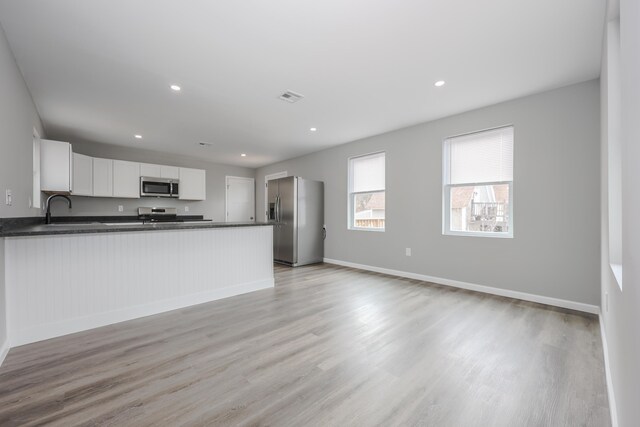 319 Mechanic St, Laconia, NH 03246 - kitchen featuring stainless steel appliances, dark countertops, light wood-style flooring, a peninsula, and baseboards
