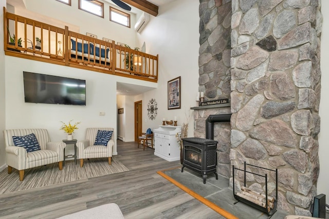 52 Meadow Ln, Belmont, NH 03220 - living room with a wood stove, a wall mounted air conditioner, wood finished floors, a high ceiling, and baseboards