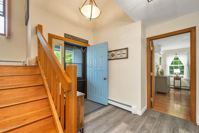52 Meadow Ln, Belmont, NH 03220 - entrance foyer with a baseboard radiator, an AC wall unit, wood finished floors, and stairs