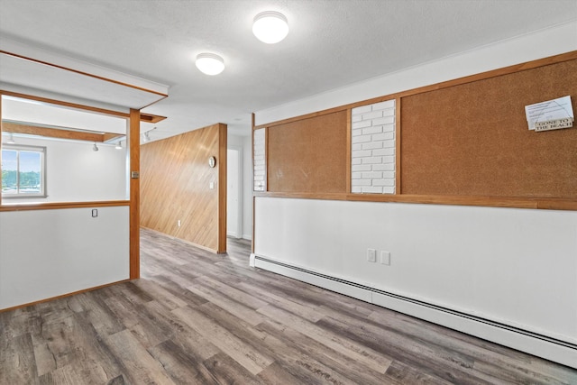 68 Kings Hwy Unit 23, Hampton, NH 03842 - empty room featuring a baseboard radiator, wood finished floors, wooden walls, and baseboards