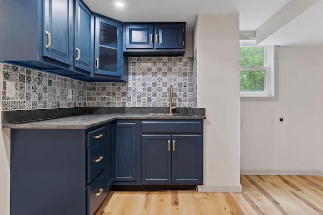 209 Craney Hill Rd, Henniker, NH 03242 - kitchen with blue cabinets, light wood-style floors, a sink, dark countertops, and decorative backsplash